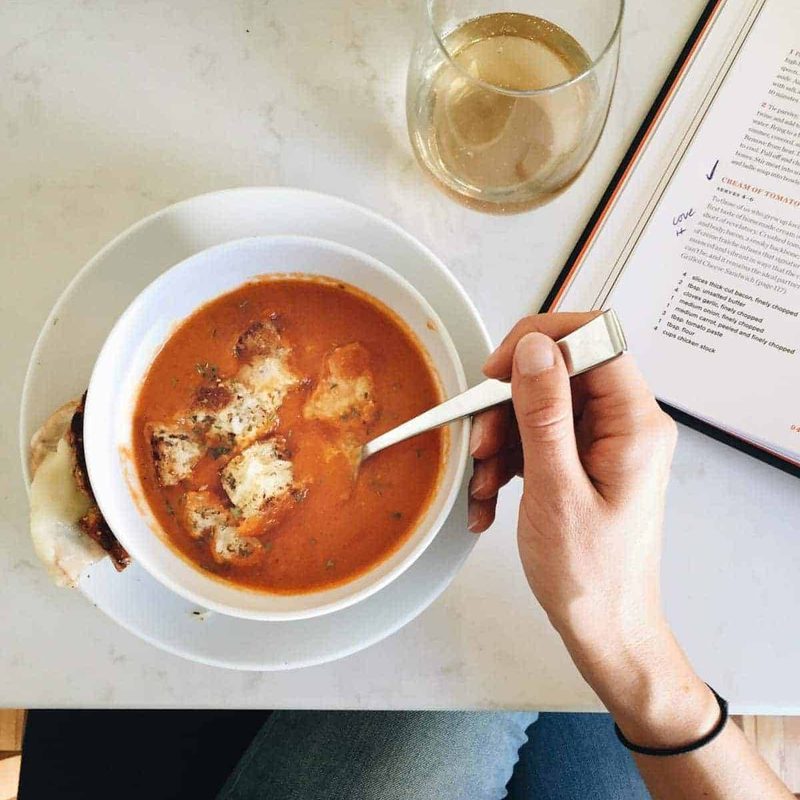 Lindsay sitting at a table eating tomato soup.