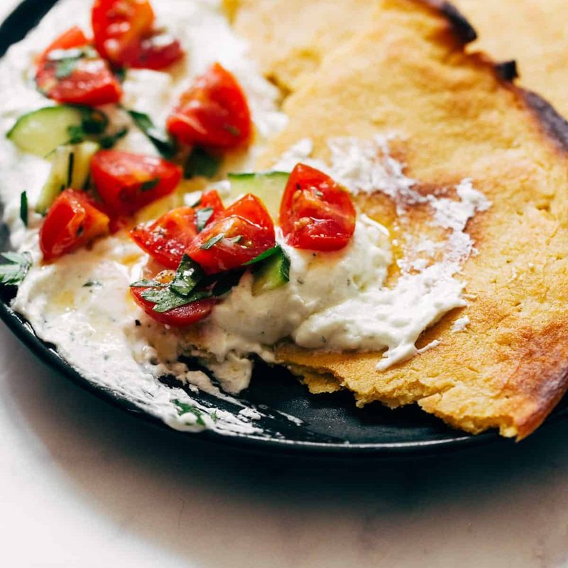 Socca with Whipped Feta and Tomato Salad on a plate.